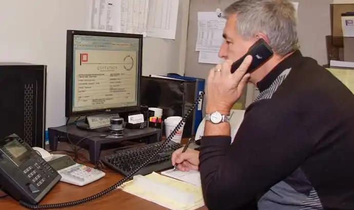 Man on the phone looking at Petro Extrusion website custom ordering